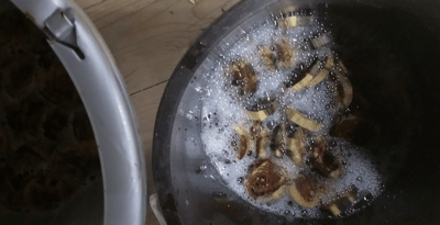 Wooden disks in buckets being stained with coffee and bleach.